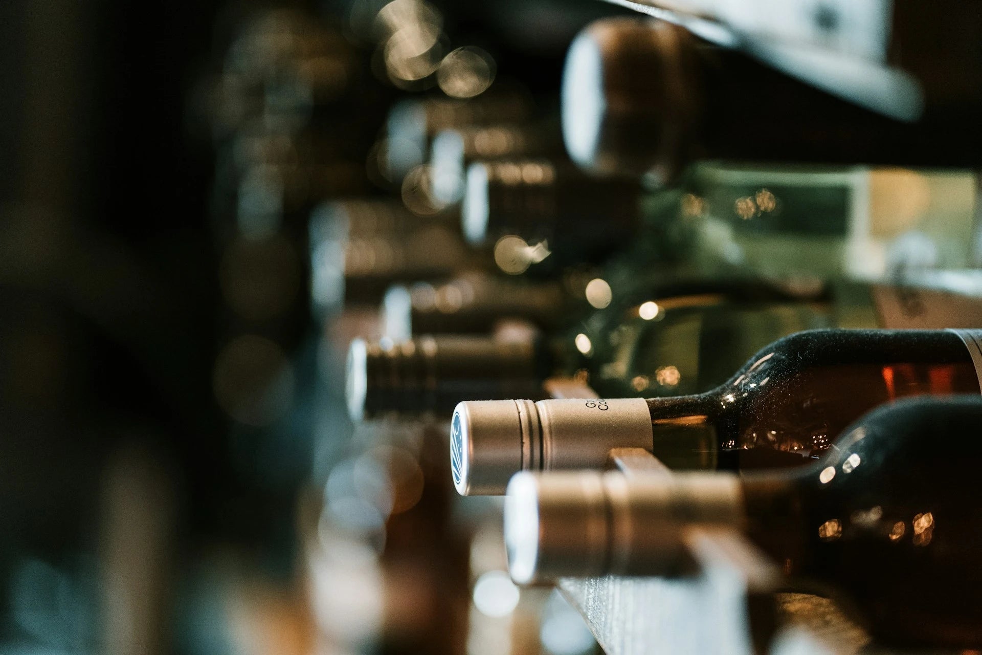 Row of wine bottles on a reflective surface with a blurred background